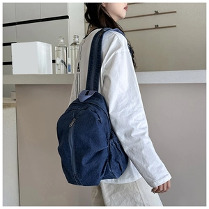 Détail d'un grand sac à dos en jean bleu marine avec poches latérales pratiques