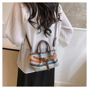 Detail of colorful striped straw woven bag with brown leather handles and shoulder strap