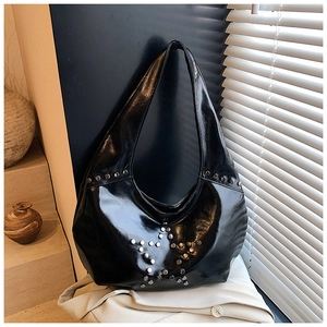 Macro detail of silver studs forming a star pattern on black glossy leather tote bag