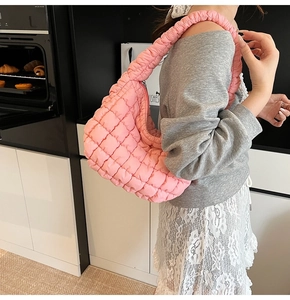 Pink quilted bubble shoulder bag with pleated handle shown worn in a lifestyle setting