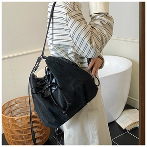 Detail view of black drawstring bucket bag with bow tie and smooth nylon texture