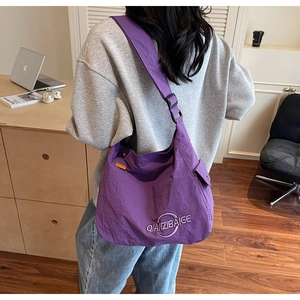 Dettaglio della borsa tote in nylon viola con ricamo, tracolla larga e tasca laterale