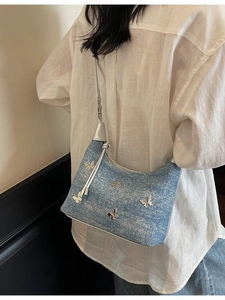 Sac à épaule en jean bleu clair avec papillons argentés porté par un mannequin style Y2K