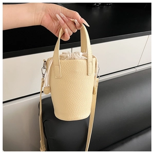 Detail view of a beige bucket bag with lychee texture and white drawstring inner pouch