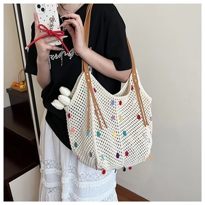 Detail of crochet tote bag with colorful 3D dots and leather strap held by a model