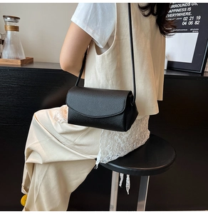 Détail d'un sac à bandoulière en cuir grainé noir avec rabat porté par un mannequin