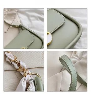 Détail du sac selle en cuir vert clair avec chaîne en foulard et boucle émaillée