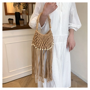 Detail of bohemian woven beige handbag with white beads and long fringe tassels