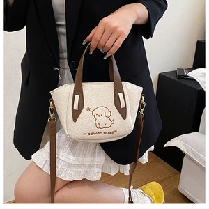 Detail of a cream canvas tote bag featuring a cute dog print and brown leather straps