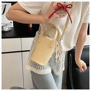 Detailed macro shot of beige bucket bag showing litchi grain texture and metal hook