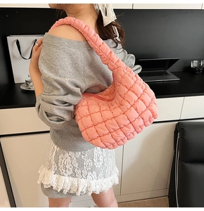 Close-up of pink ruched cloud bag featuring pleated nylon texture and crescent shape