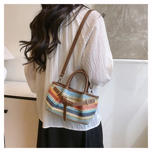 Detail of colorful wavy woven straw tote bag with brown leather handles and strap