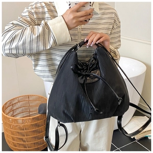 Detail view of a black drawstring backpack with ripple texture nylon and bow accent