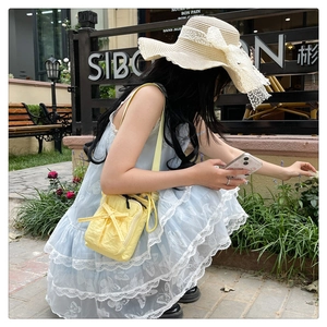 Close-up of light yellow nylon crossbody bag featuring a decorative bow on the front