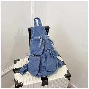 Detail der blauen Denim-Umhängetasche mit vielen Taschen auf einem Koffer