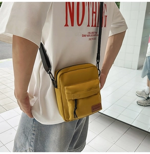 Detail of yellow nylon crossbody bag with front pocket and adjustable black strap