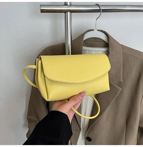 Détail d'un sac bandoulière en cuir grainé jaune vif avec rabat élégant et fine sangle
