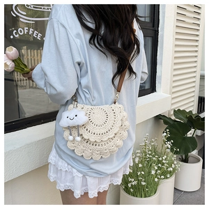 Detail of cream knit saddle bag with wavy layers and brown leather strap on model