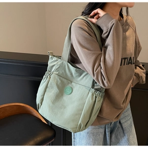 Sage green canvas tote bag detail on model showing large capacity and drawstring side pockets