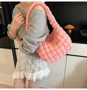 Detail of pink quilted puff shoulder bag with waffle texture shown on model