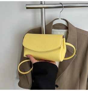 Détail du sac bandoulière en cuir jaune grainé avec rabat et bords arrondis lisses