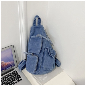 Details einer blauen Jeans-Umhängetasche mit drei Reißverschlusstaschen und breitem Gurt