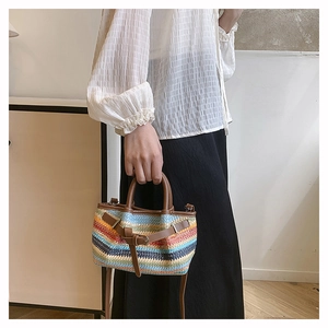 Close-up of a colorful rainbow woven tote bag with brown leather handles and strap