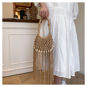 Macro detail of handmade bohemian woven bag with elegant fringe and white bead accents