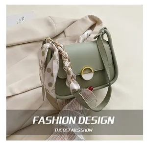 Détail du sac selle vert clair avec ruban imprimé cerises et fermoir rond doré