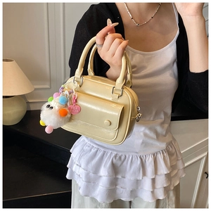 Detail of cream leather handbag featuring a cute plush heart charm and front pocket flap