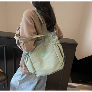 Detail of light green large capacity tote bag with drawstring side pockets and logo
