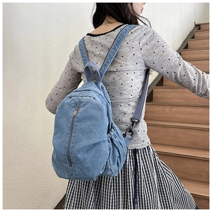 Détail du sac à dos en denim bleu clair avec poches latérales à cordon et sangles grises