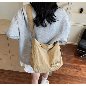 Dettaglio della borsa tote a mezzaluna in nylon kaki indossata da una modella in interni