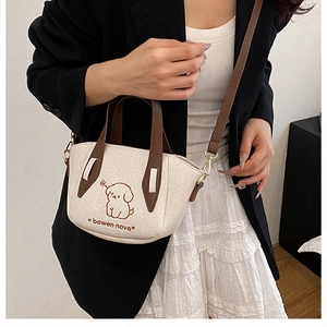 Detail of cream crossbody bag with cute dog embroidery and brown leather straps