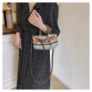 Detail of colorful striped woven crossbody bag with brown leather handles and strap