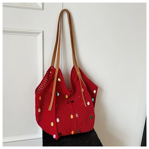 Macro detail of red knitted tote bag featuring colorful sequins and leather strap