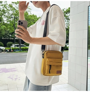 Close-up of yellow canvas crossbody bag featuring a front pocket with black drawstring detail
