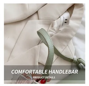 Gros plan de la poignée en cuir d'un sac besace vert sauge avec surpiqûres précises