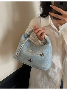 Denim light blue handbag with silver handles and butterfly charms shown on a model