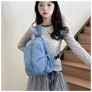 Détail du sac bandoulière en jean bleu clair avec poche latérale et fermeture éclair