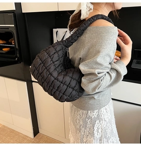 Detail of black quilted cloud bag with puffy shoulder strap and textured fabric