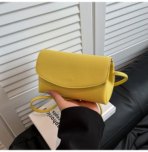 Détail du sac à bandoulière jaune en cuir synthétique à texture litchi et rabat arrondi