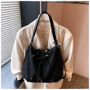 Macro view of black nylon tote bag with unique cross-tied ribbon bow and pleated texture