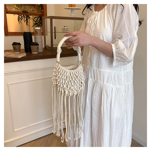 Detailed close-up of white bohemian fringe rope woven handbag held by a person
