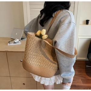 Détail du grand sac cabas en paille ajourée porté à l'épaule par un mannequin de dos