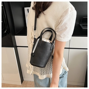 Detail of black lychee texture mini bucket bag with white drawstring canvas inner pouch