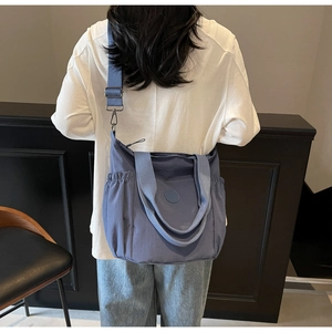 Detail of dark blue canvas tote featuring adjustable straps and side drawstring pocket