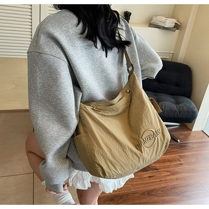 Borsa tote minimalista in tela kaki portata a spalla con ampio dettaglio della tasca laterale