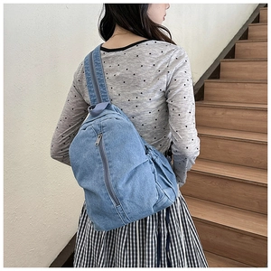 Détail du sac de poitrine en denim bleu clair avec fermeture éclair verticale et bandoulière