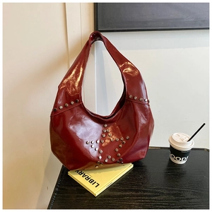 Macro shot of punk style hobo bag with wine red patent leather and star rivet details